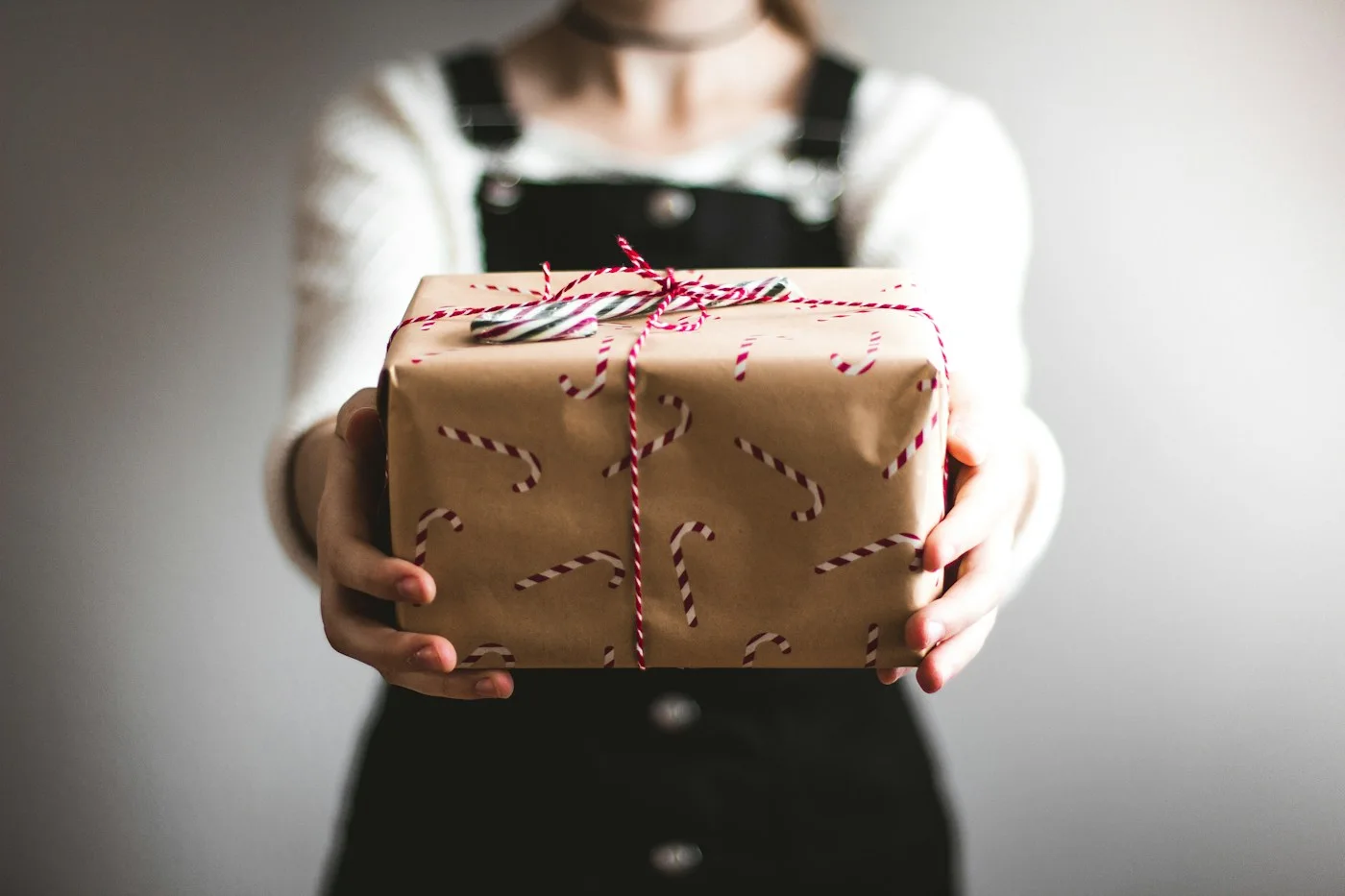 Person offering a wrapped gift tied with string