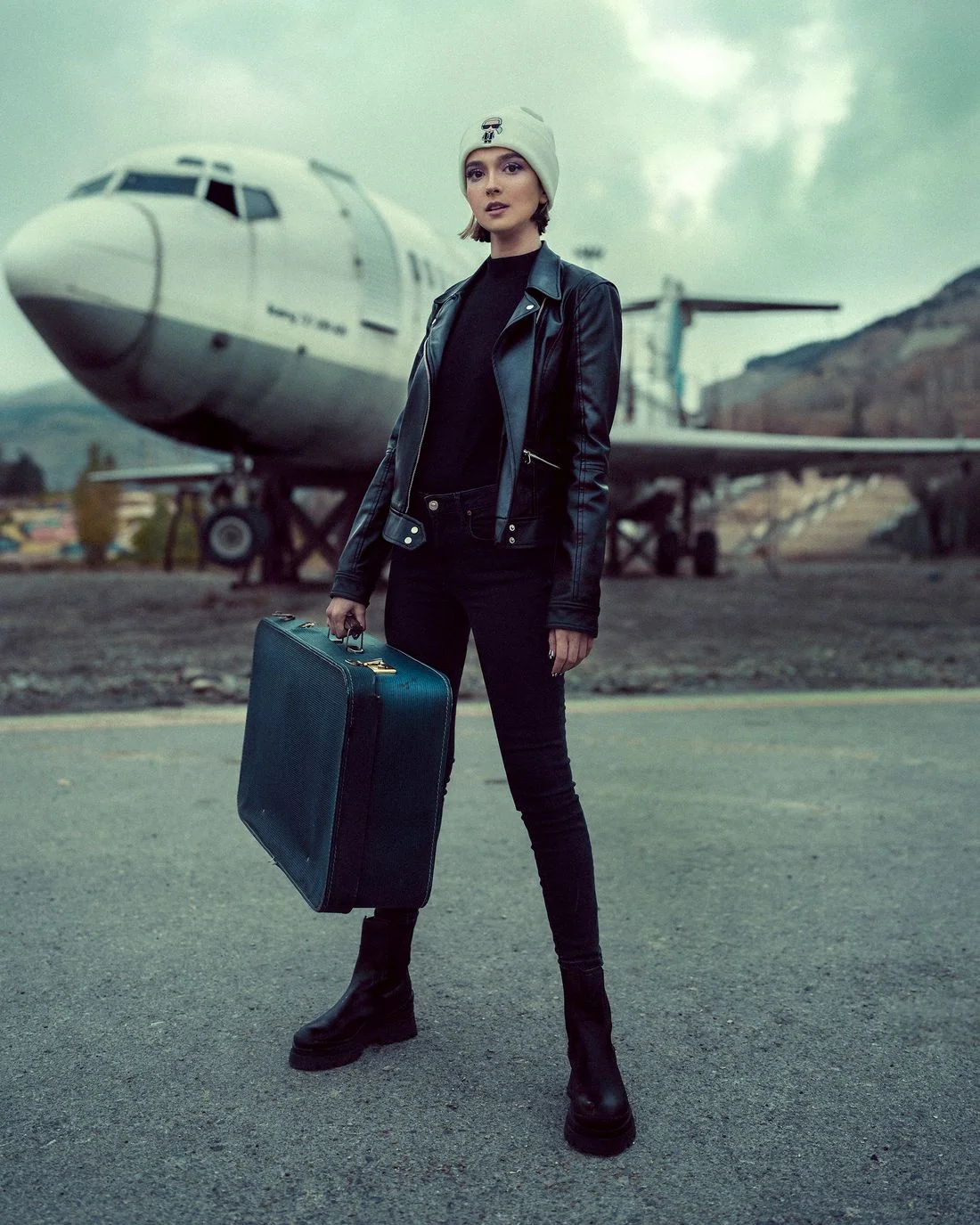 A traveler holding a case near an airplane