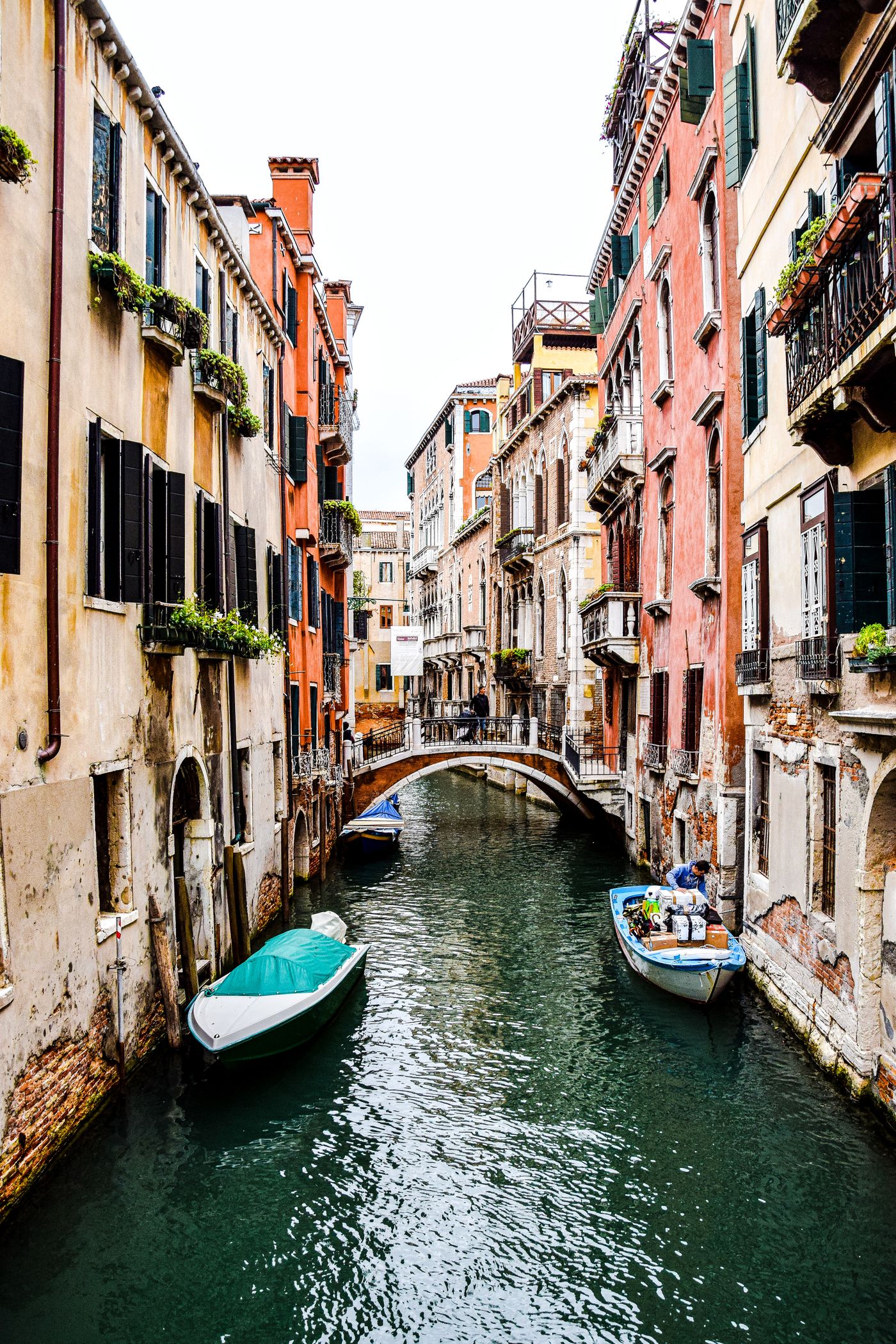 Colourful buildings and a small arched bridge beside a Venice canal
