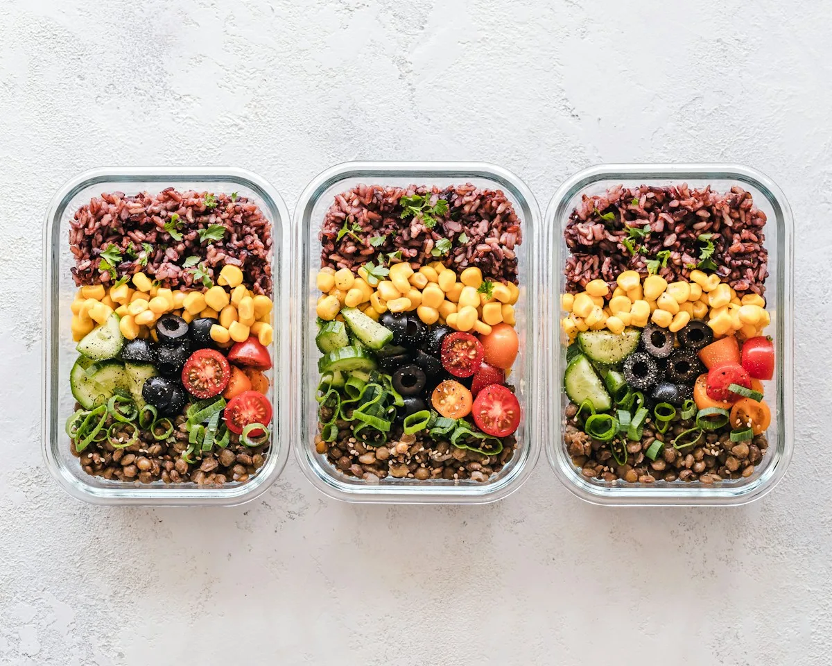 Three prepared meal containers with colorful vegetables and grains.