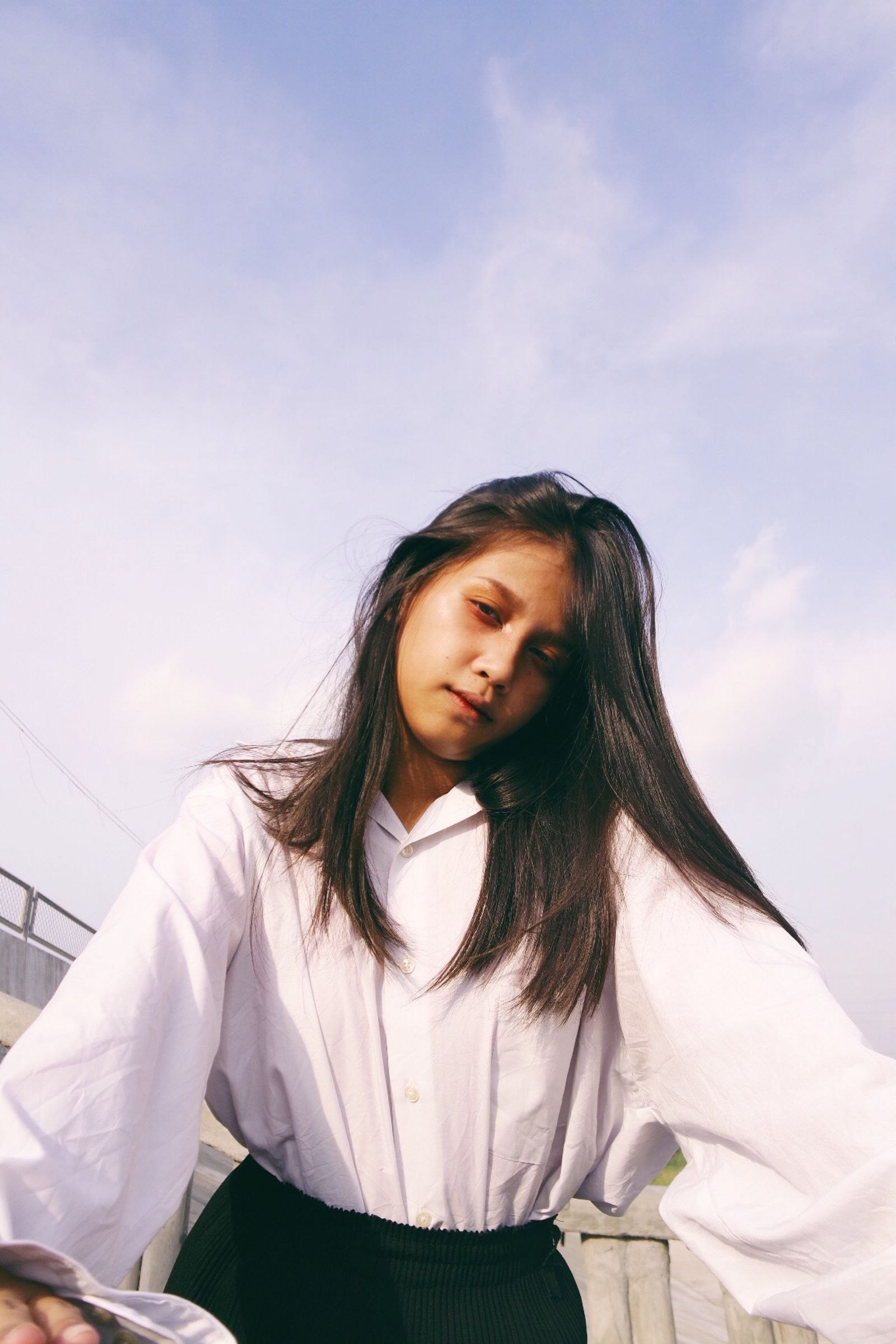 A woman wearing a loose pale blouse outdoors.