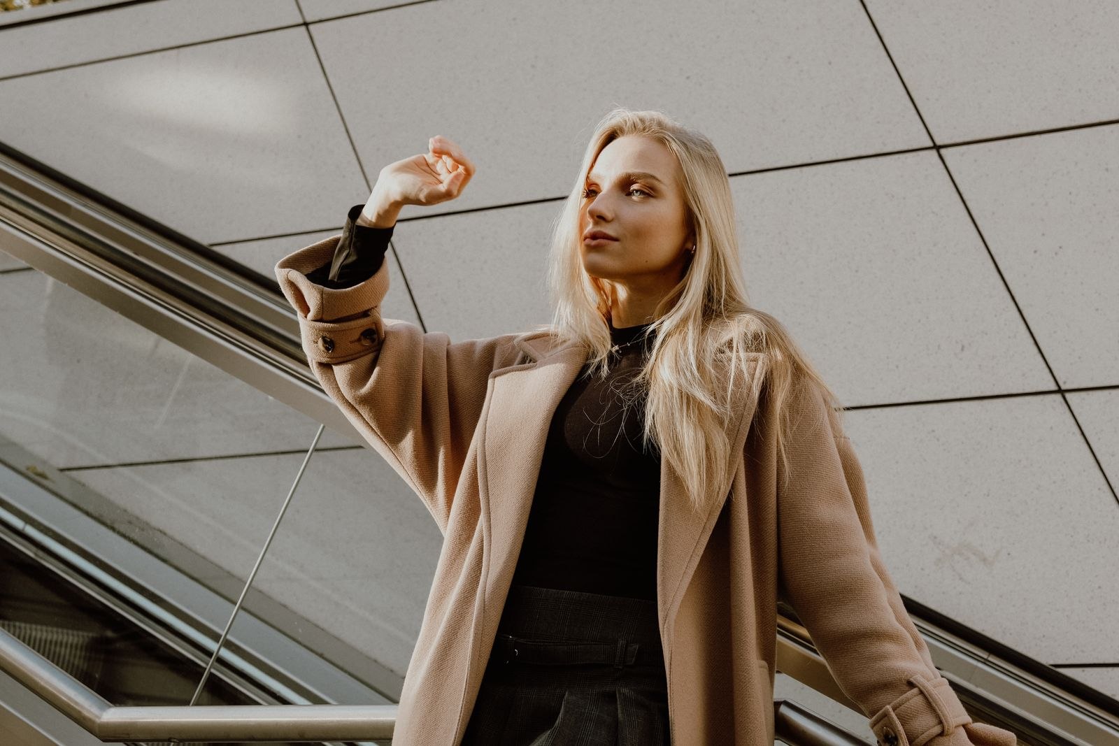 A woman wearing a long coat in an urban setting.