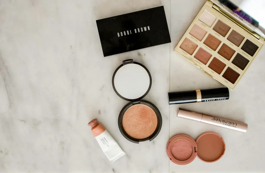 Makeup palettes and compacts arranged on a pale surface.