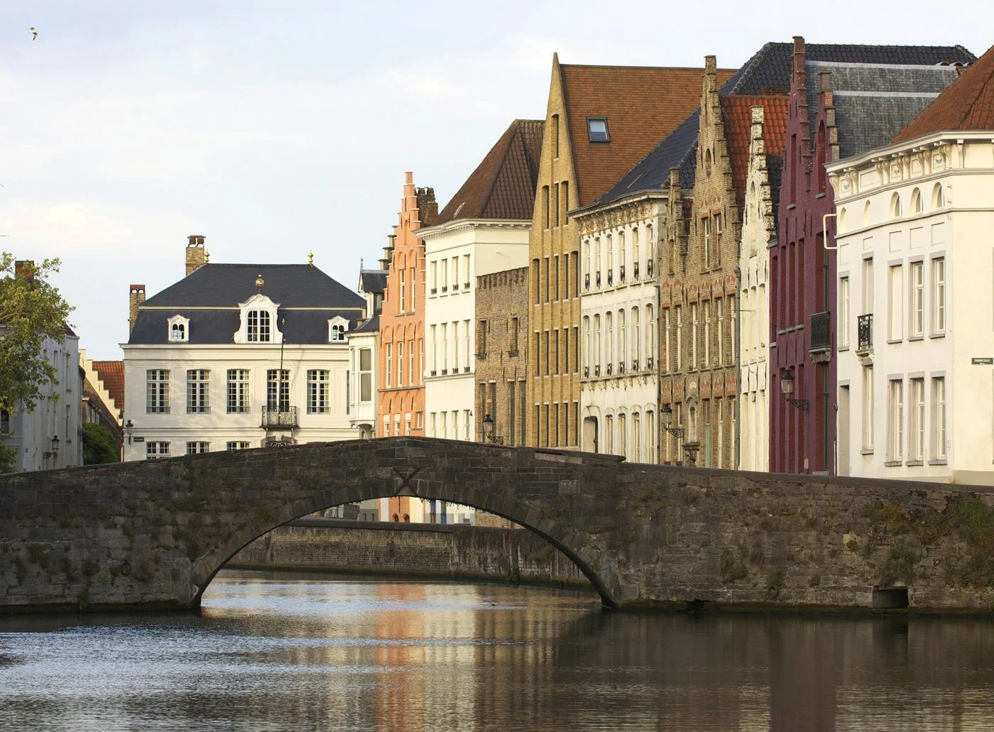 Historic buildings and a stone bridge beside a canal in Bruges.